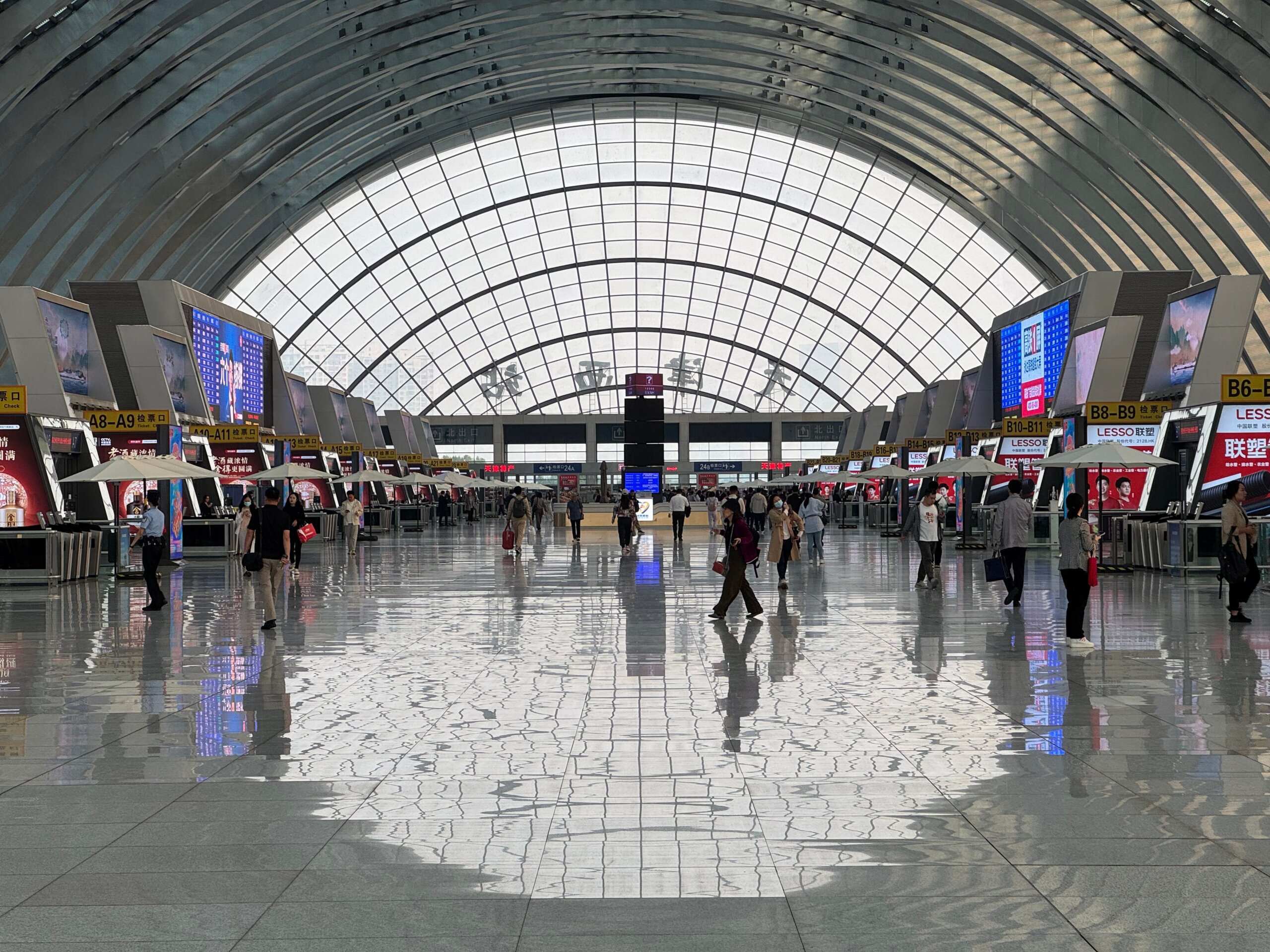 A bustling modern airport terminal with geometric ceiling design and reflective floors.